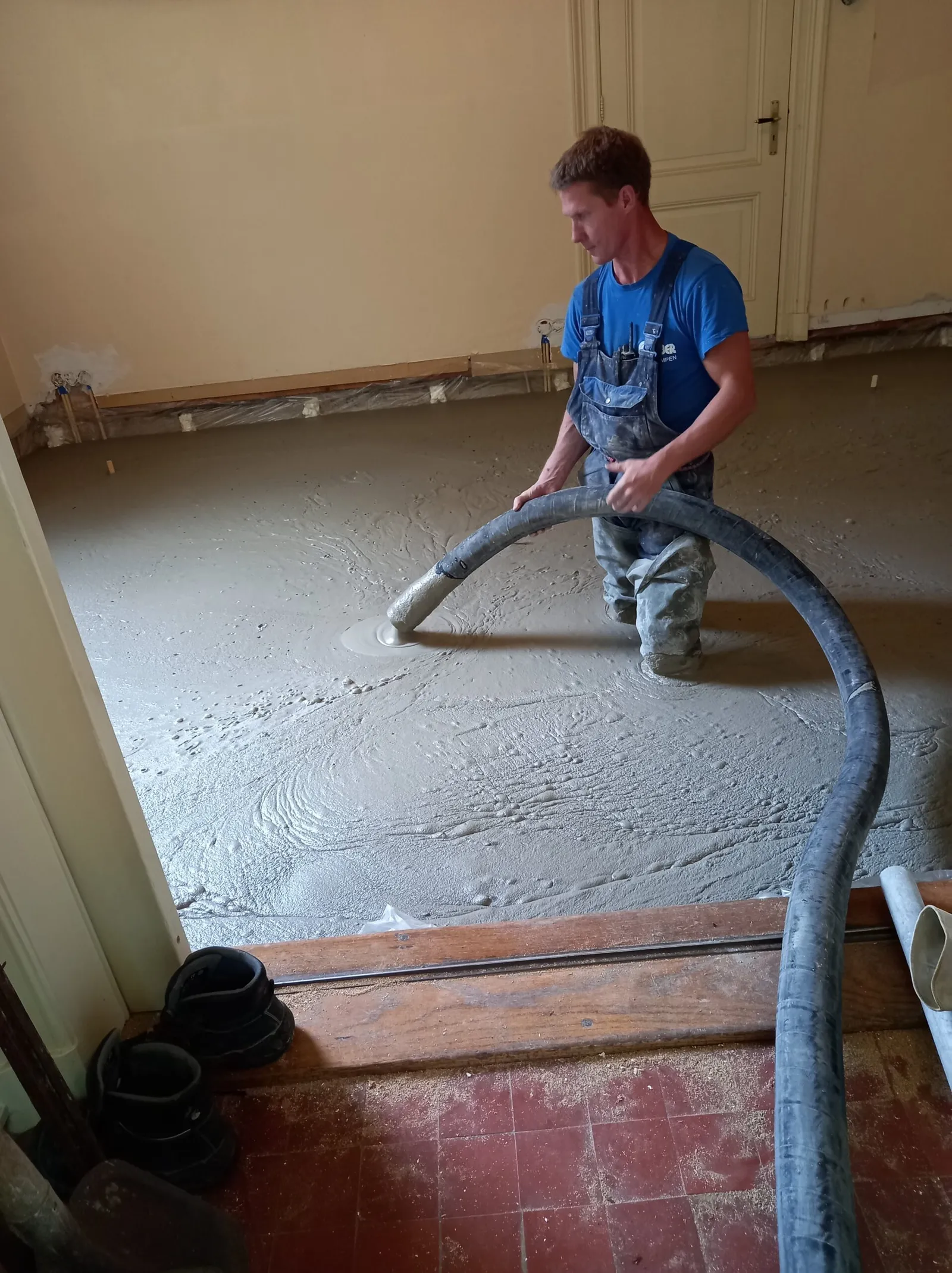Vakman plaatst schuimbeton met een slang in een woning